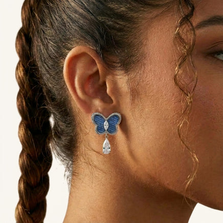Close-up of blue denim butterfly earring with silver-tone beaded frame, marquise zirconia center and teardrop crystal drop | Olaty