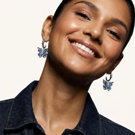 Blue denim butterfly drop earrings worn with sculptural barbed wire inspired hoops and zirconia accents | Olaty