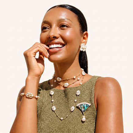 Iridescent fan-shaped abalone shell brooch with crystal detailing and pearl drop styled on green dress | Olaty