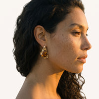 Molten gold-tone gemstone statement earring worn on ear showing its organic sculptural drop silhouette | Olaty