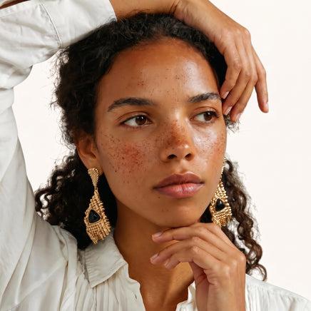 Gold-tone geometric grid statement earrings with black triangular resin accents worn on model | Olaty