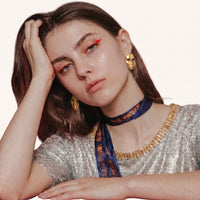 Gold sculptural face earrings with cascading chain fringe worn as artistic statement jewelry | Olaty