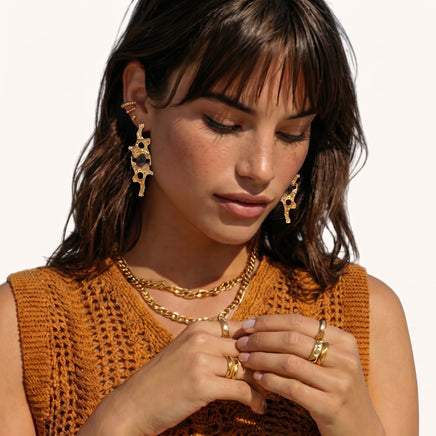 Gold-tone abstract resin statement earrings with sculptural openwork design worn on model | Olaty
