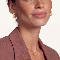 Model wearing baroque gold huggie hoop earrings with ribbed texture and delicate floral details | Olaty