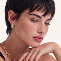 Model wearing braided pavé huggie hoop earring with brushed gold texture and cubic zirconia accents | Olaty