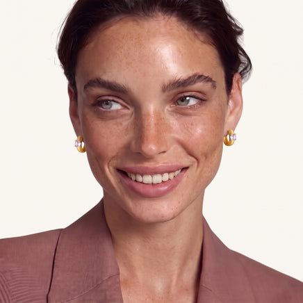 Model wearing brushed solitaire huggie hoop earrings with round cubic zirconia stones | Olaty