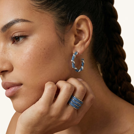 Close-up of blue denim fabric hoop earring with polished silver-tone twisted metal worn on the ear | Olaty