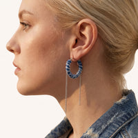 Close-up of Denim Dream hoop earring styled with denim, showing blue fabric texture and dangling silver-tone chains | Olaty