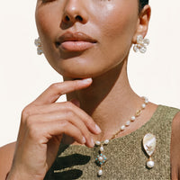 Iridescent shell bird brooch with baroque pearl drop styled on an olive green top | Olaty