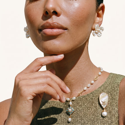 Iridescent shell bird brooch with baroque pearl drop styled on an olive green top | Olaty
