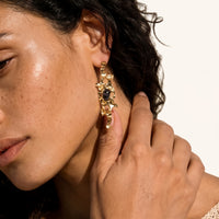 Close-up of sculptural gold-tone earring with dark resin accent and organic cutout details worn on model | Olaty