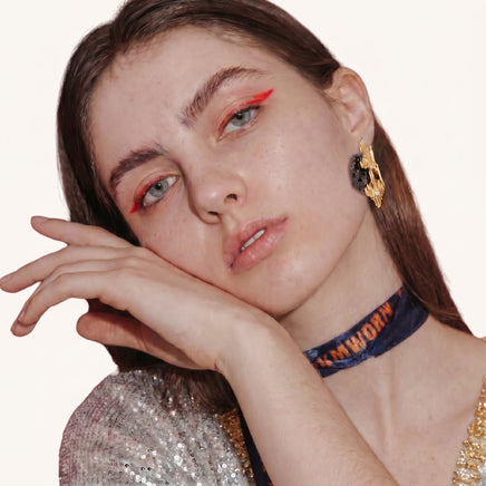 Sculptural gold-tone statement earrings with dark resin and rhinestone accents worn on model | Olaty