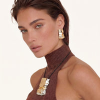 Gold and silver sculptural pendant necklace with matching statement earring worn on model | Olaty