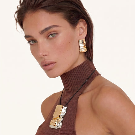 Gold and silver sculptural pendant necklace with matching statement earring worn on model | Olaty
