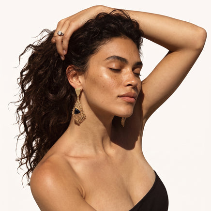Architectural gold-tone statement earrings with black resin centers and textured grid drops worn on model | Olaty