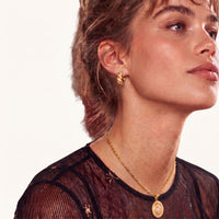Side view of model wearing braided pavé huggie hoop earring with alternating gold and cubic zirconia details | Olaty