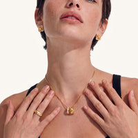 Model wearing braided clover stud earrings with brushed gold texture and sparkling cubic zirconia halo | Olaty