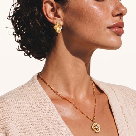 Close-up of model wearing Bloom floral stud earrings with brushed gold petals and cubic zirconia sparkle | Olaty