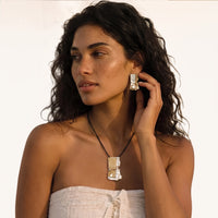 Two-tone abstract pendant necklace and matching sculptural statement earring styled on model | Olaty