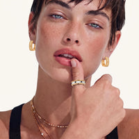 Close-up of model wearing textured baroque huggie hoop earrings in warm gold finish | Olaty