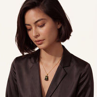 Forest Gold Amber Necklace styled on a model in a black blazer with green amber pendant and gold-plated sterling silver chain | Olaty