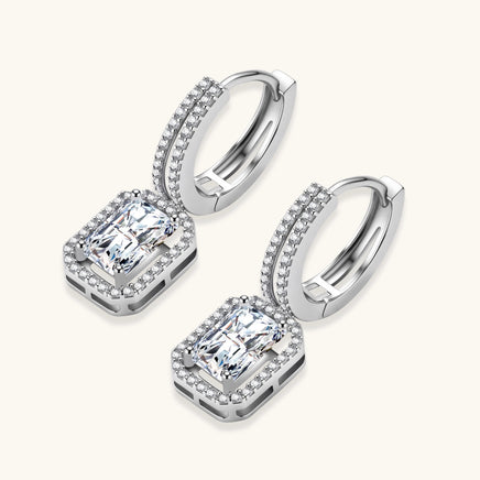 Emerald cut moissanite drop earrings angled view with pavé halo and silver huggie hoops | Olaty