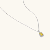 Angled view of the yellow emerald cut moissanite pendant necklace with diamond halo in white gold | Olaty