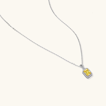 Angled view of the yellow emerald cut moissanite pendant necklace with diamond halo in white gold | Olaty