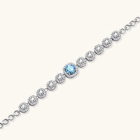 Angled view of Azure Tennis Bracelet highlighting blue moissanite centerpiece and sparkling round halo-set stones | Olaty