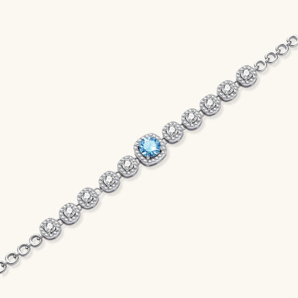 Angled view of Azure Tennis Bracelet highlighting blue moissanite centerpiece and sparkling round halo-set stones | Olaty