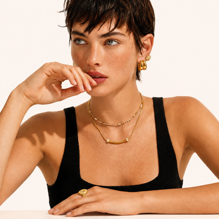 Model wearing Curved Spark Bar Necklace layered with gold jewelry | Olaty