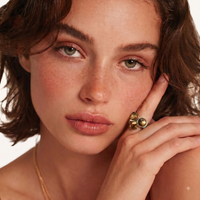 Model wearing golden-brown three-stone statement ring in close-up portrait | Olaty