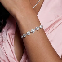 Moissanite heart bracelet worn on wrist featuring graduated sparkling heart motifs in sterling silver | Olaty