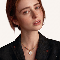 Model wearing gold-tone necklace with grey stone beads and iridescent clover-shaped pendant | Olaty