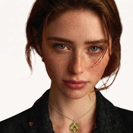 Model wearing emerald green oval pendant necklace with gold detailing and zirconia accents | Olaty