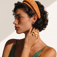 Model wearing oversized gold-tone flower statement ring with central white pearl | Olaty