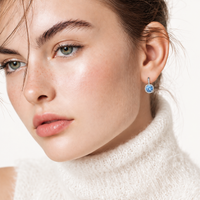 Woman wearing GRA certified blue moissanite diamond celestial halo drop earring in sterling silver | Olaty