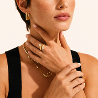 Model wearing Bamboo Sculpted Huggie Hoops with layered gold jewelry | Olaty