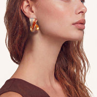 Model wearing twisted sculptural statement hoop earring with red and blue enamel detailing | Olaty