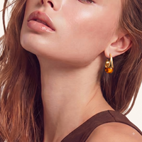 Model wearing sculptural amber resin drop earrings with polished gold finish | Olaty