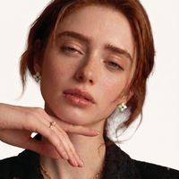 Model wearing gold-tone Mother of Pearl clover stud earrings with green gemstone centers | Olaty