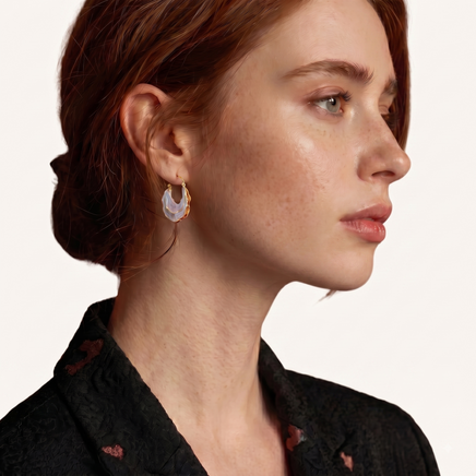 Side profile of model wearing iridescent blue and pink sculptural shell hoop earring | Olaty