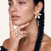 Model wearing oversized white enamel orchid statement earring with gold-tone petals | Olaty