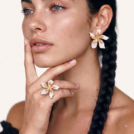 Model wearing oversized white enamel orchid statement earring with gold-tone petals | Olaty