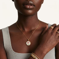 Close-up of model wearing rose floral pendant necklace with pink enamel and pearl design | Olaty