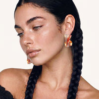 Model wearing colorful twisted hoop earrings with sculptural ribbon design | Olaty