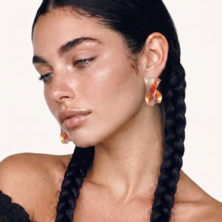 Model wearing colorful twisted hoop earrings with sculptural ribbon design | Olaty