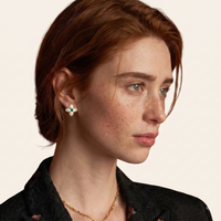 Side portrait of model wearing Mother of Pearl quatrefoil stud earrings with green gemstone centers | Olaty