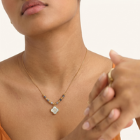 Close-up of model wearing gold-tone grey stone bead necklace with iridescent clover-shaped pendant | Olaty