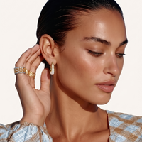 Model wearing liquid curve white resin hoop earrings with polished gold-tone frames | Olaty